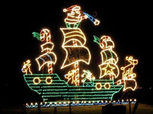 A brightly lit Christmas ship display with Santa and festive decorations, set against a dark night sky.