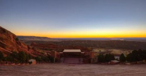 Panoramic view of Red Rocks Amphitheatre at sunset, showcasing the stage and surrounding natural landscape.