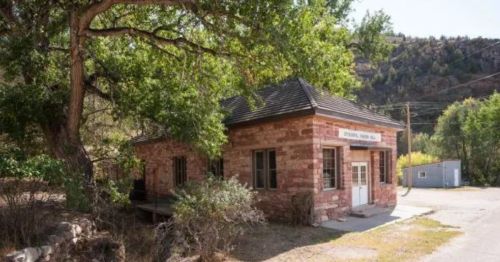 A small stone building surrounded by trees, with a sign reading "Historical Fire Hall" in a rural setting.