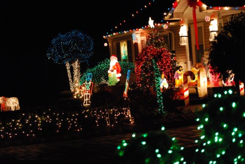 A festive house decorated with colorful Christmas lights, featuring Santa, trees, and various holiday figures.