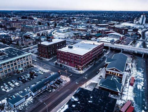 Aerial view of a snowy town with buildings, roads, and parked cars, showcasing a mix of urban and natural landscapes.