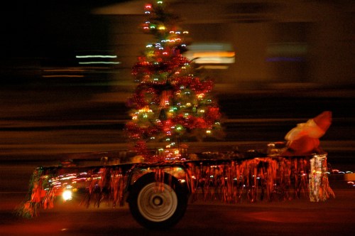 A decorated cart with a Christmas tree and lights, moving quickly, creating a blurred effect.