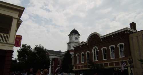 A historic town square featuring a clock tower and brick buildings under a cloudy sky.