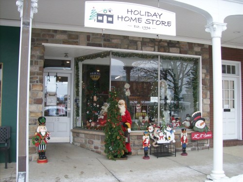 A festive storefront decorated for the holidays, featuring Santa, nutcrackers, and various seasonal decorations.