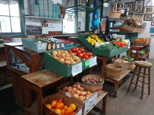 A vibrant market stall filled with fresh fruits and vegetables, including apples, tomatoes, and squash, in wooden crates.