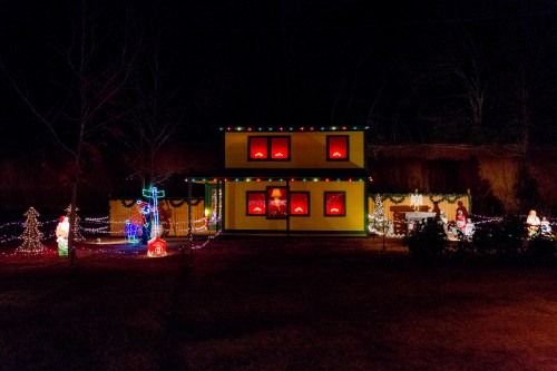 A brightly lit house decorated with colorful Christmas lights and festive decorations in a nighttime setting.