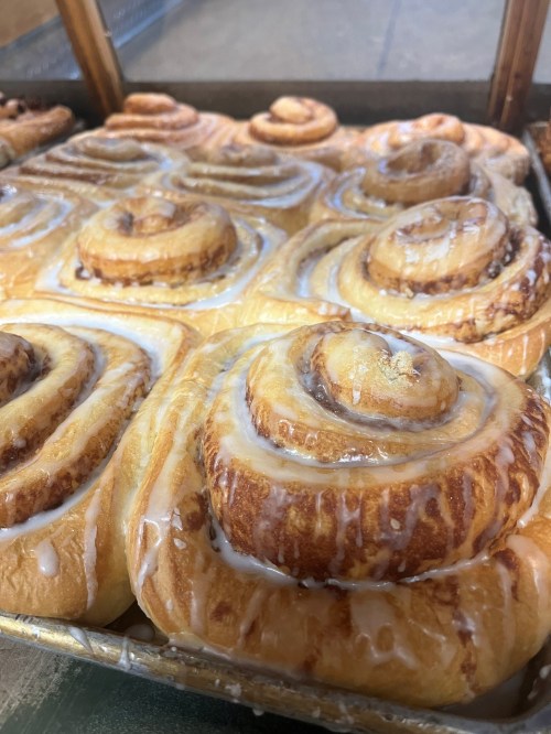 A tray of freshly baked cinnamon rolls drizzled with icing, showcasing their golden-brown swirls.
