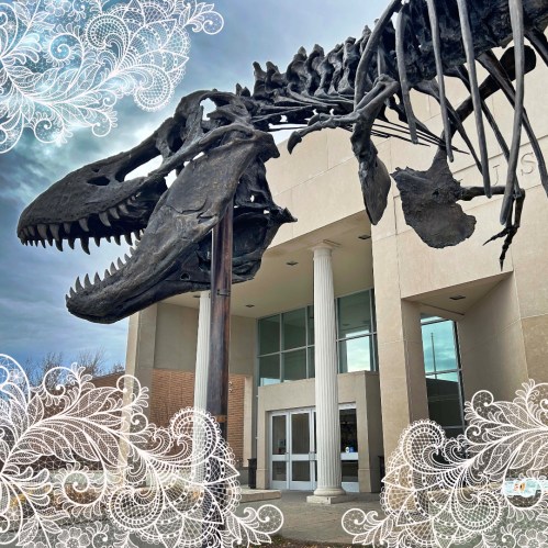A large dinosaur skeleton stands outside a building, framed by decorative white swirls.