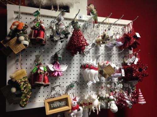A display of various Christmas ornaments, including trees, stockings, and figurines, hanging on a pegboard.
