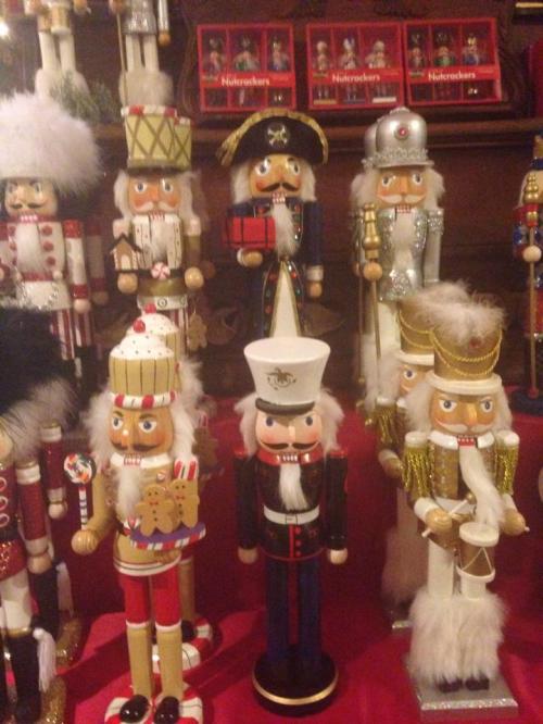 A collection of colorful nutcracker figurines in various costumes displayed on a red tablecloth.