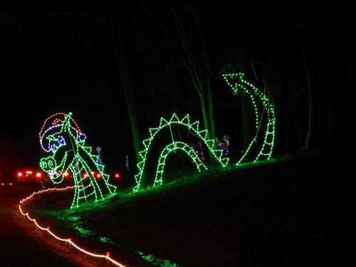 A colorful dragon made of green lights, illuminated against a dark background, with a festive holiday atmosphere.