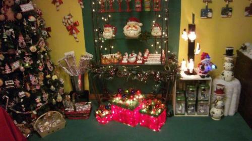 A festive display featuring a decorated Christmas tree, colorful lights, and holiday-themed decorations on shelves.