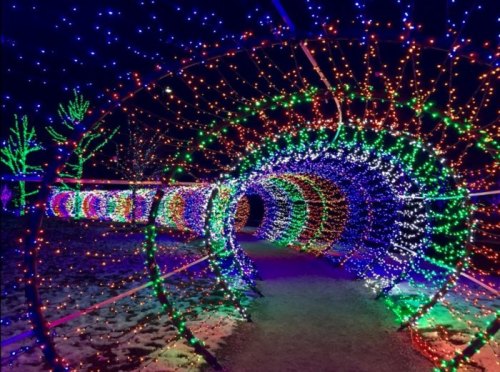 A colorful tunnel of lights in various hues, creating a festive and enchanting atmosphere at night.