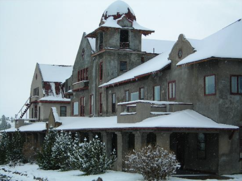 A large, historic building covered in snow, featuring a distinctive dome and multiple architectural details.