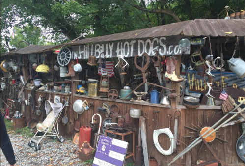 A rustic display of vintage items and memorabilia on a wooden structure, with a sign for "Billy Hot Dogs."