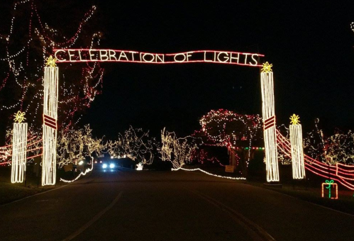 A festive archway reading "Celebration of Lights" surrounded by colorful holiday lights at night.