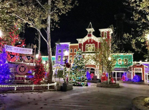 A festive building adorned with colorful Christmas lights and decorated trees, set in a nighttime winter scene.