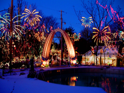 A colorful display of holiday lights and decorations around a pool, with vibrant fireworks-like patterns in the background.