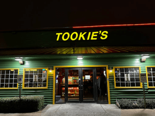 Exterior of Tookie's restaurant at night, featuring a green facade and bright yellow signage.