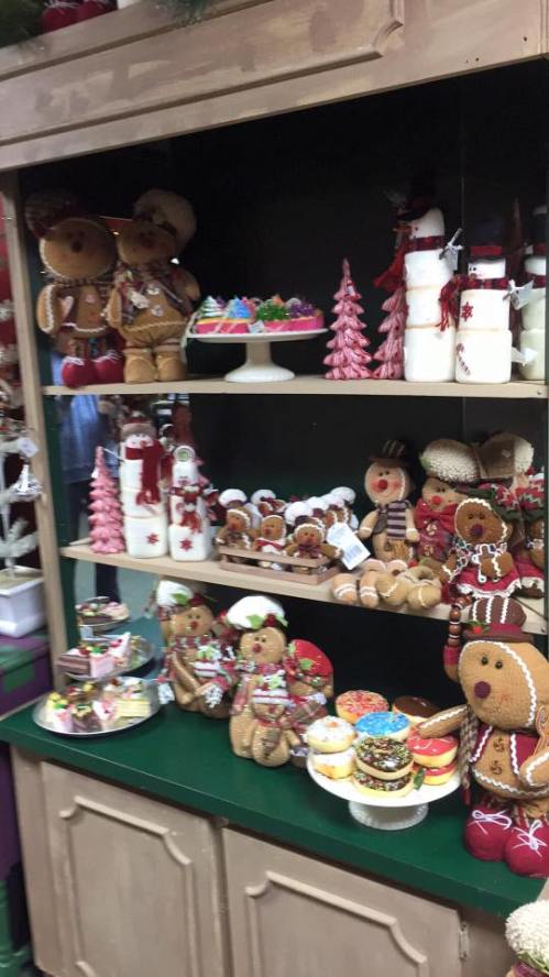 A festive display of gingerbread cookies, decorated treats, and holiday decorations on a wooden shelf.