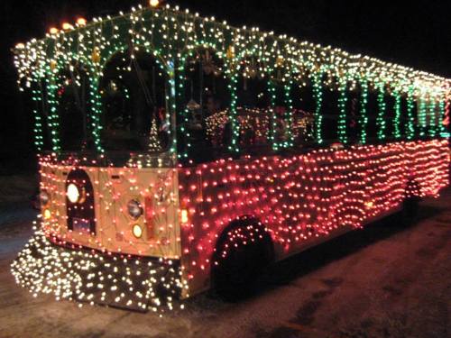 A brightly lit trolley covered in colorful Christmas lights, glowing in the night.