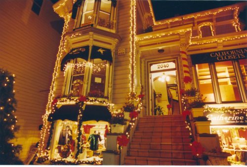 A beautifully decorated Victorian house at night, adorned with festive lights and holiday decorations.