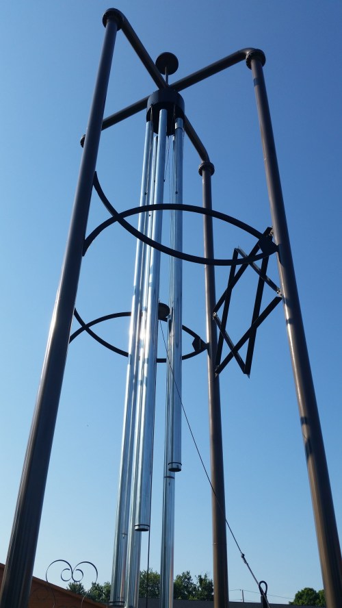 A large metal structure with vertical tubes and circular elements against a clear blue sky.