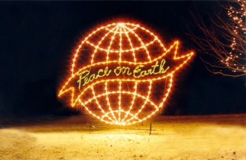 A glowing globe made of lights with the phrase "Peace on Earth" displayed across it, set against a dark background.