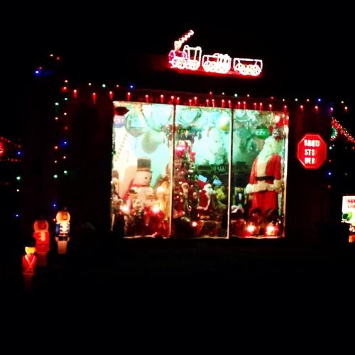 A festive display of Christmas lights and decorations, featuring Santa and various holiday ornaments in a window.