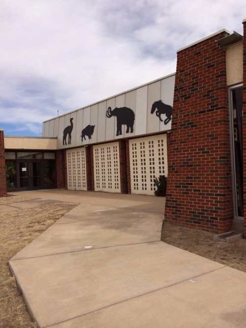 A building with animal silhouettes on the facade, featuring a pathway leading to the entrance.