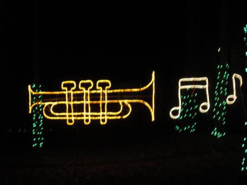 A glowing yellow trumpet and musical notes outlined in lights against a dark background.