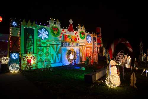 Colorful holiday display with lights, decorations, and a snowman, set against a dark night sky.