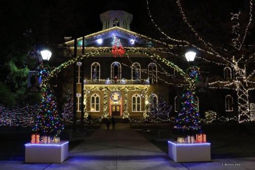 A beautifully lit building adorned with festive decorations and colorful lights, surrounded by trees and lampposts.