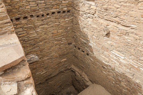 A view of ancient stone walls forming a deep, rectangular structure with small openings along the upper edges.