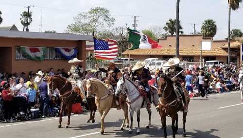 A parade featuring riders on horseback, holding flags, with a crowd watching along the street.