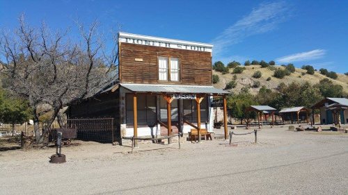 A rustic wooden building labeled "General Store" in a desert landscape with sparse trees and hills in the background.