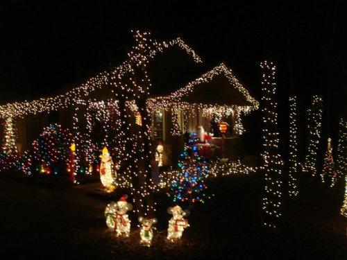 A house decorated with colorful Christmas lights and festive figures, glowing brightly in the night.