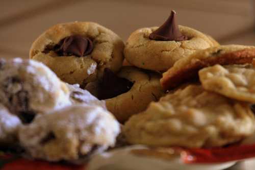 A close-up of assorted cookies, including chocolate chip and powdered sugar varieties, arranged on a plate.