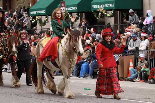 A festive parade scene with a girl in a green and red outfit riding a horse, accompanied by cheerful participants.