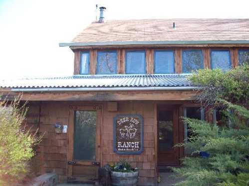 A rustic wooden ranch house with a sign reading "Deer Run Ranch" and a welcoming entrance surrounded by greenery.