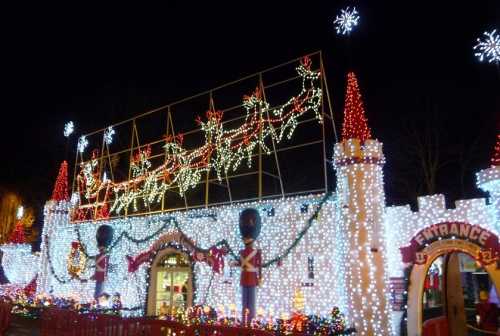 A brightly lit holiday display featuring a castle, Santa's sleigh, and festive decorations at night.