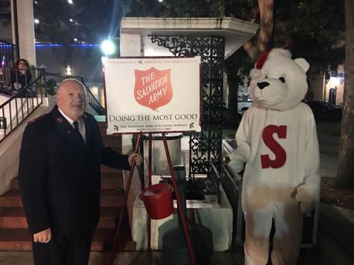 A man in a Salvation Army uniform stands next to a person in a polar bear costume by a donation kettle.