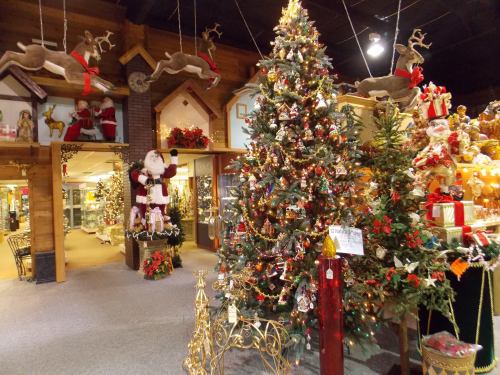 A festive holiday display featuring a decorated Christmas tree, Santa figure, and reindeer decorations in a cozy shop.