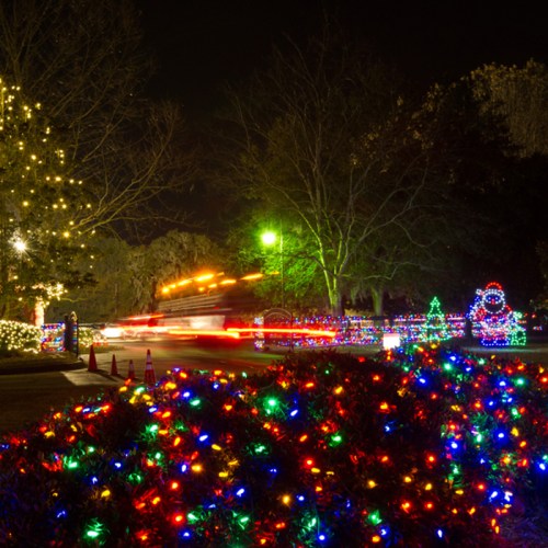 A festive scene featuring colorful holiday lights, a decorated tree, and a Santa figure in a nighttime setting.