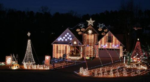 A beautifully decorated house with colorful Christmas lights, featuring trees, stars, and festive displays in the yard.