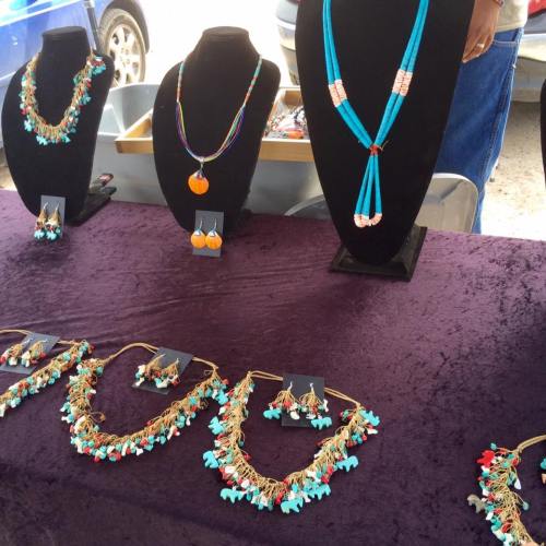 Colorful jewelry display featuring necklaces and earrings on a dark tablecloth at an outdoor market.