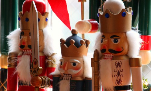 Three colorful nutcracker figures, each wearing crowns and holding different props, displayed in a festive setting.
