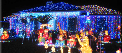 A house decorated with colorful Christmas lights, featuring festive figures like Santa and snowmen in the yard.