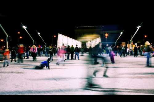 A bustling ice skating rink at night, filled with people skating and enjoying the festive atmosphere.