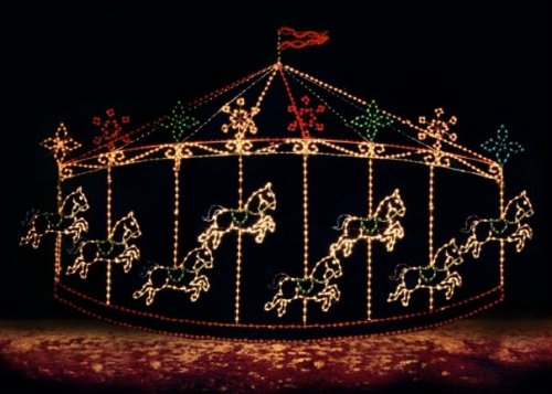 A brightly lit carousel with colorful horses, set against a dark background.